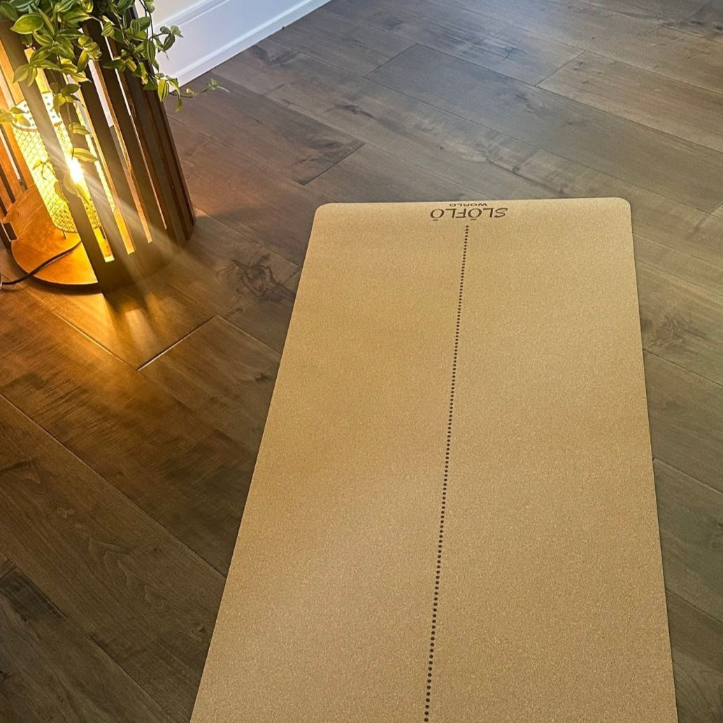 Yoga mat on a wooden floor with a plant in the background